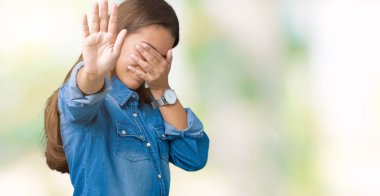 Üzerinde mavi kot gömlek giyen genç güzel esmer kadın izole elleriyle gözlerini kapsayan arka plan ve stop jest ile acı ve korku ifadesi. Utandım ve negatif kavramı.