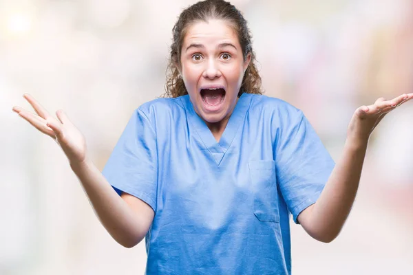 年轻的黑发医生女孩穿着护士或外科医生制服在孤立的背景庆祝疯狂和惊奇为成功与胳膊抬起和睁开眼睛尖叫兴奋 优胜者概念 — 图库照片