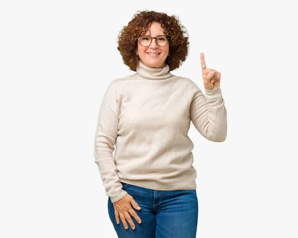分離背景表示と自信を持って 幸せな笑みを浮かべて 指番号のいずれかで上向きにタートルネックのセーターとメガネを着て美しい中間エイガー年配の女性 — ストック写真