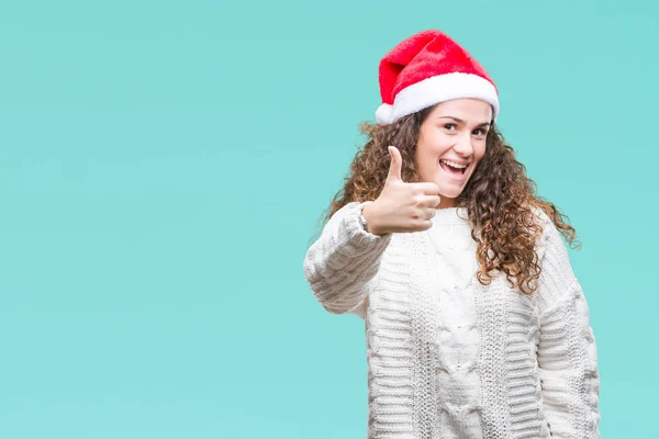 年轻的黑发女孩戴着圣诞帽在孤立的背景做快乐的大拇指与手的手势 通过显示成功来批准镜头的表达 — 图库照片