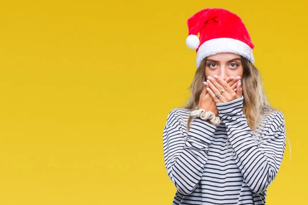 美しい若い金髪女性の孤立した背景のミスのための手で口を覆っているショックを受けた上クリスマス帽子をかぶっています 秘密の概念 — ストック写真