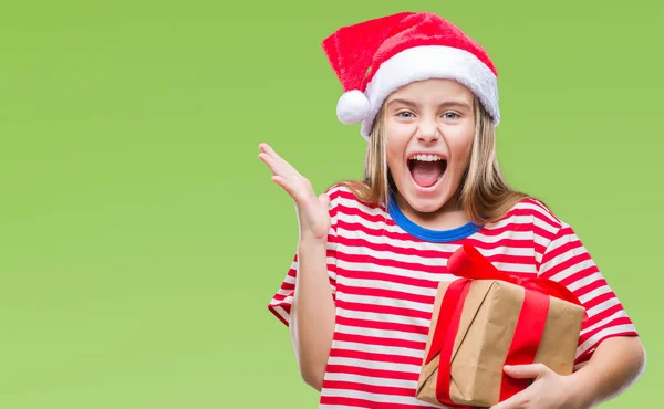 年轻美丽的女孩戴着圣诞帽 拿着礼物在孤立的背景非常高兴和兴奋 获胜者表达庆祝胜利尖叫与灿烂的笑容和举起的手 — 图库照片