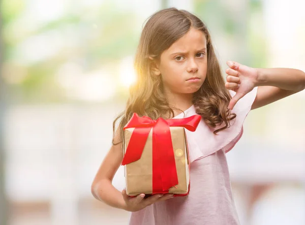 怒った顔 ダウン親指で嫌悪感を示すマイナス記号 拒絶反応の概念で贈り物を保持しているヒスパニックのブルネットの少女 — ストック写真