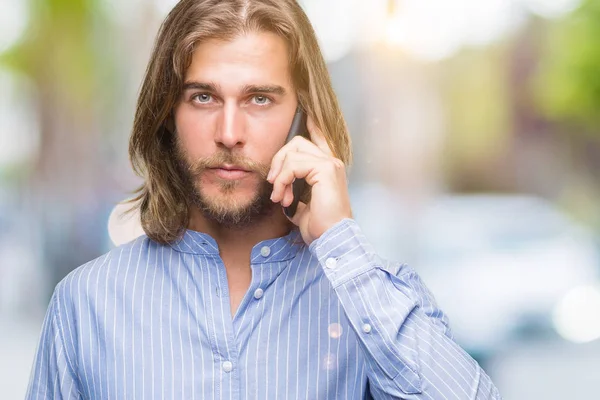 Молодой Красивый Мужчина Длинными Волосами Изолированном Фоне Разговаривает Телефону Уверенным — стоковое фото