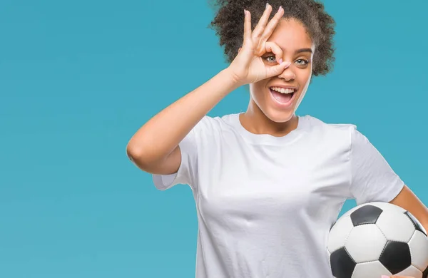 年轻美丽的美国黑人举行足球足球在孤立的背景和快乐的脸微笑做 标志用手在眼睛看通过手指 — 图库照片