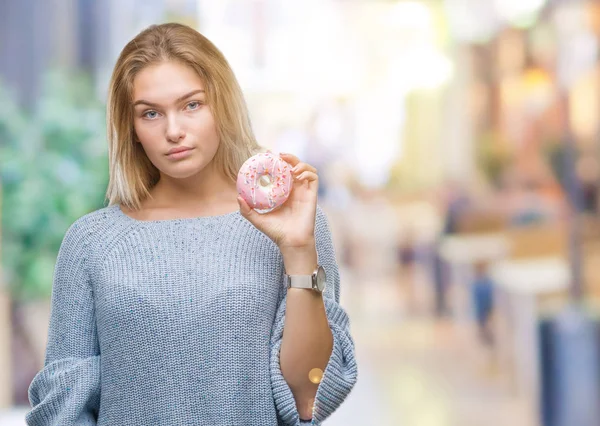 Acımak yüz ciddi düşünüyorum üstünde kendine güvenen bir ifade ile izole arka plan üzerinde tatlı çörek yiyen genç kafkas kadın