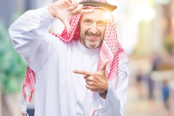 笑顔の幸せそうな顔で指と手作りフレーム分離の背景にクーフィーヤを着てシニアのアラブ人 創造性と写真のコンセプト — ストック写真