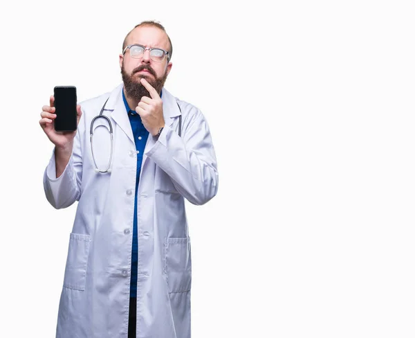 年轻的医生在孤立的背景下展示智能手机屏幕严肃的脸思考问题 非常混乱的想法 — 图库照片