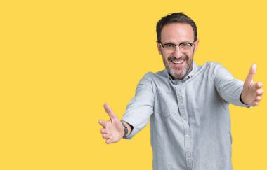 Sarılmak için kollarını açarak gülümseyerek kameraya bakarak izole arka plan üzerinde gözlük takan yakışıklı orta yaş zarif komuta sizde. Neşeli ifade kucaklayan mutluluk.