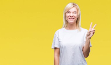 Gösterilen ve parmakları ile işaret izole arka plan üzerinde beyaz t-shirt giyen genç güzel sarışın kadın ikincisi ise kendinden emin ve mutlu gülümseyerek.