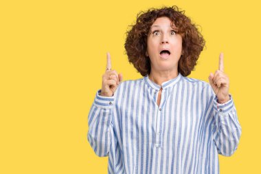 Hayret ve yukarıya bakıyor ve parmakları ile işaret ve silah kaldırdı sürpriz arka plan üzerinde Donanma forması giyen güzel orta ager üst düzey kadın izole.