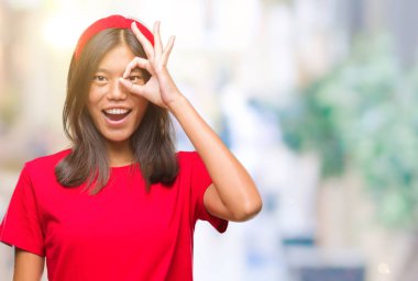 Genç Asyalı kadın gülümsüyor, parmakları ile mutlu yüz üzerinden seyir göz el ile ok jest yapıyor izole arka plan üzerinde.