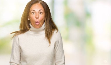 Güzel orta yaş yetişkin kadın giyiyor kış kazak korkuyor ve şok sürpriz ifade ile izole arka plan üzerinde korku ve yüz heyecanlı.