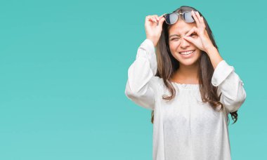 Genç güzel Arap kadın gülümsüyor, parmakları ile mutlu yüz üzerinden seyir göz el ile ok jest yapıyor izole arka plan üzerinde güneş gözlüğü takıyor.
