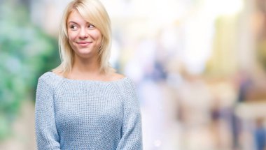 Görünümlü yan ve dik dik bakma uzağa düşünce gülümseyen izole arka plan üzerinde kış kazak giyen genç güzel sarışın kadın.