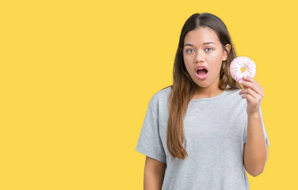 Jovem Bela Mulher Comendo Donut Rosa Sobre Fundo Isolado Assustado — Fotografia de Stock