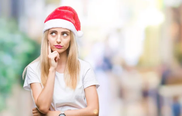 あごを考えて質問 物思いにふける式の手で隔離された背景に若い金髪美人クリスマス帽子 思いやりのある顔をして笑っています 疑いのコンセプト — ストック写真