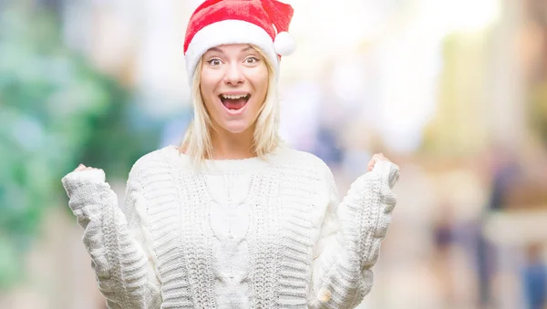 年轻美丽的金发女子戴着圣诞节帽子在孤立的背景庆祝惊讶和惊讶的成功与双臂举起和睁开眼睛 获奖者概念 — 图库照片