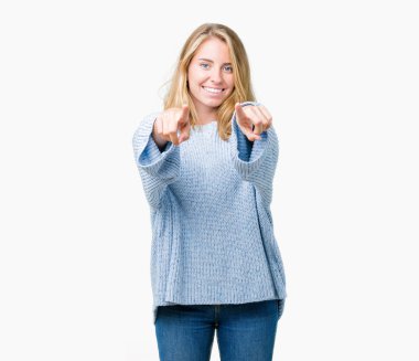 Mavi kazak izole üzerinde giyen güzel genç kadın arka plan size işaret ve parmaklar, kamerayla olumlu ve neşeli gülümseyen