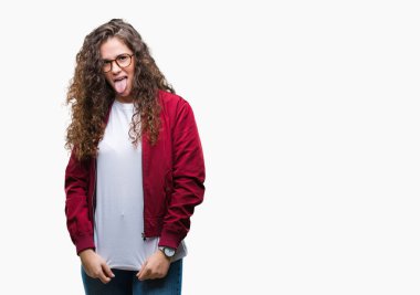 Güzel esmer kıvırcık saçlı Genç kız giyiyor ceket ve gözlük dilini izole arka plan üzerinde mutlu komik ifade ile dışarı. Duygu kavramı.