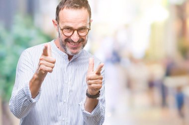 Fotoğraf makinesi ile mutlu ve komik yüz için parmakları işaret izole arka plan üzerinde gözlük takan orta yaş ağarmış komuta sizde. İyi enerji ve vibes.