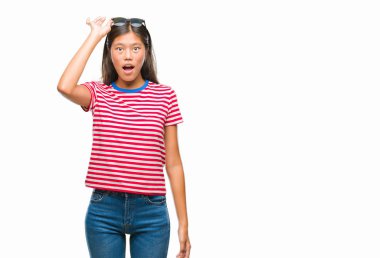 Genç Asyalı kadın korkuyor ve şok sürpriz ifade, korku ve heyecan yüz ile izole arka plan üzerinde güneş gözlüğü takıyor.