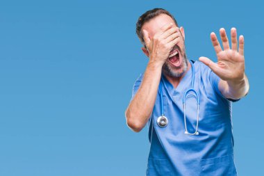 Orta yaş ağarmış kıdemli Doktor adam üzerinde tıbbi üniforma izole elleriyle gözlerini kapsayan arka plan ve stop jest ile acı ve korku ifadesi. Utandım ve negatif kavramı.