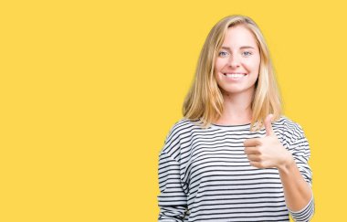 Hareketi el ile mutlu yaşasın yapıyor izole arka plan üzerinde çizgili süveter giyen güzel genç kadın. Başarı gösteren kameraya bakarak ifade onaylama.