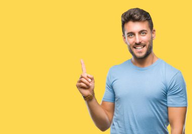 Kameraya bakarak yan el ve parmak ile işaret eden genç yakışıklı adam yüzünde kocaman bir gülümseme ile izole arka plan üzerinde.