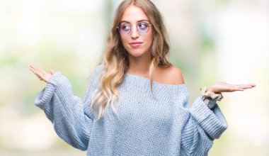 Güzel genç sarışın kadın üzerinde güneş gözlüğü takıyor arka plan clueless ve şaşkın bir ifadeyle kollar ve eller kaldırdı izole. Şüphe kavramı.