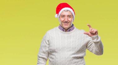 İzole arka plan gülümseyen ve boyutu işaret parmaklı ararken ve kamera işi el ile kendinden emin eller üzerinde Noel şapka giymiş yakışıklı komuta sizde. Ölçü kavramı.