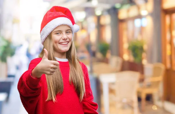 美しい少女ハッピー サムズアップ手でジェスチャーをして孤立した背景にクリスマス帽子をかぶっています 成功を示すと カメラを見て式を承認します — ストック写真