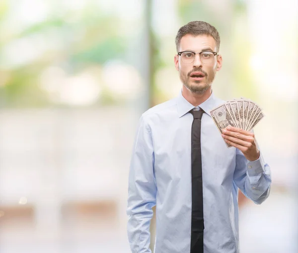 Young Hipster Business Man Holding Dollars Scared Shock Surprise Face — Stock Photo, Image
