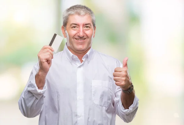 笑顔の サイン 優秀な兆候を親指をやって幸せな孤立の背景の上クレジット カードを持ってハンサムな年配の男性 — ストック写真