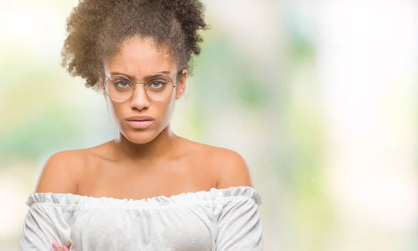 年轻的美国黑人妇女戴着眼镜在孤立的背景怀疑和紧张 不赞成的表情与交叉的武器 消极的人 — 图库照片