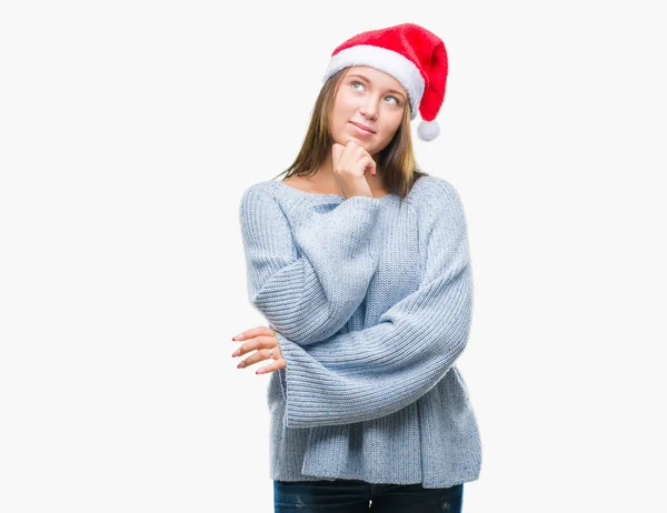 若い美しい白人女性のあごを考えて質問 物思いにふける式の手で隔離された背景にクリスマス帽子をかぶっています 思いやりのある顔をして笑っています 疑いのコンセプト — ストック写真