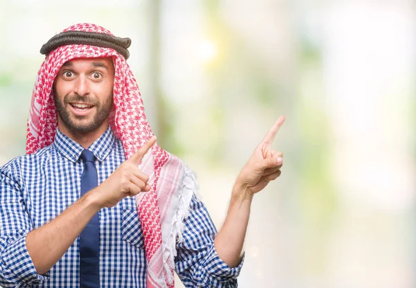 笑顔で側に つの手と指で指しているカメラを見て孤立の背景にクーフィーヤを着た若いハンサムなアラビアン ビジネス男 — ストック写真