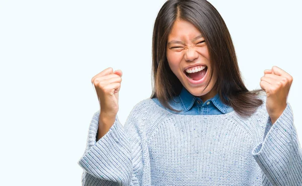 若いアジア女性は笑みを浮かべて 成功のために叫んで非常に幸せと興奮の腕を上げ 勝者のジェスチャを行う分離の背景に冬のセーターを着ています お祝いのコンセプト — ストック写真