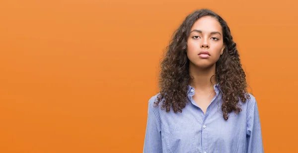 Young hispanic business woman with serious expression on face. Simple and natural looking at the camera.