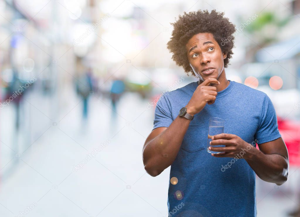 Afro american man drinking glass of water over isolated background serious face thinking about question, very confused idea