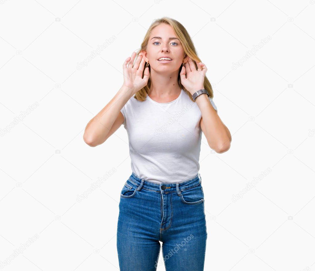 Beautiful young woman wearing casual white t-shirt over isolated background Trying to hear both hands on ear gesture, curious for gossip. Hearing problem, deaf