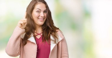 Artı boyutu genç kadın güzel üzerinde kış palto giyiyor arka plan işaret parmağı kadar başarılı fikirle izole. Çıktıktan ve mutlu. Bir numara.