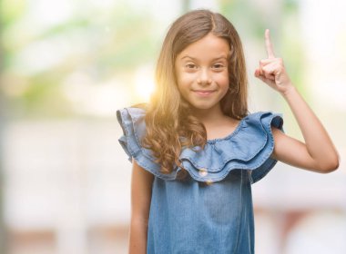 Esmer Latin kız giyiyor denim bir fikirle sürpriz elbise ya da gülen yüz, bir numara ile işaret parmağı soru