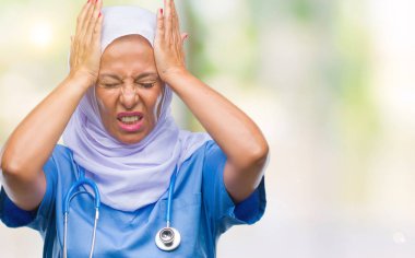 Çünkü çaresiz ve stresli baş ağrısı acı izole arka plan üzerinde hijab giyen orta yaş üst düzey Arap hemşire kadın ağrı ve migren. Ellerini kafasına.