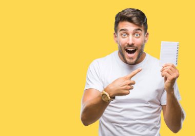 Defter izole arka plan üzerinde çok mutlu el ve parmak ile işaret tutan genç yakışıklı adam