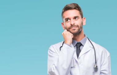 Genç yakışıklı adam çene düşünme hakkında soru, dalgın ifade üzerine el ile izole arka plan üzerinde doktor. Düşünceli yüzüyle gülümsüyor. Şüphe kavramı.