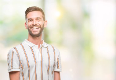 Yakışıklı delikanlı uzak tarafına yüzünde, doğal ifade gülümseme ile seyir izole arka plan üzerinde. Kendine güvenen gülüyor.