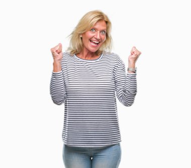 Orta yaş sarışın kadın kutluyor izole arka plan üzerinde şaşırttı ve başarı için kaldırdı kollarını açarak hayret ve gözleri açık. Kazanan kavramı.