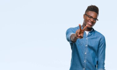 Afrikalı-Amerikalı genç zafer işareti yapıyor parmak gösterilen kamera seyir gülümseyen izole arka plan üzerinde. İki numaralı.