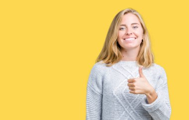 Güzel genç kadın hareketi el ile mutlu yaşasın yapıyor izole arka plan üzerinde kış kazak giyiyor. Başarı gösteren kameraya bakarak ifade onaylama.